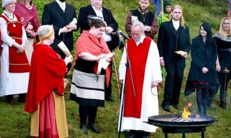 Personer i ceremoniella kläder samlas kring en eld utomhus